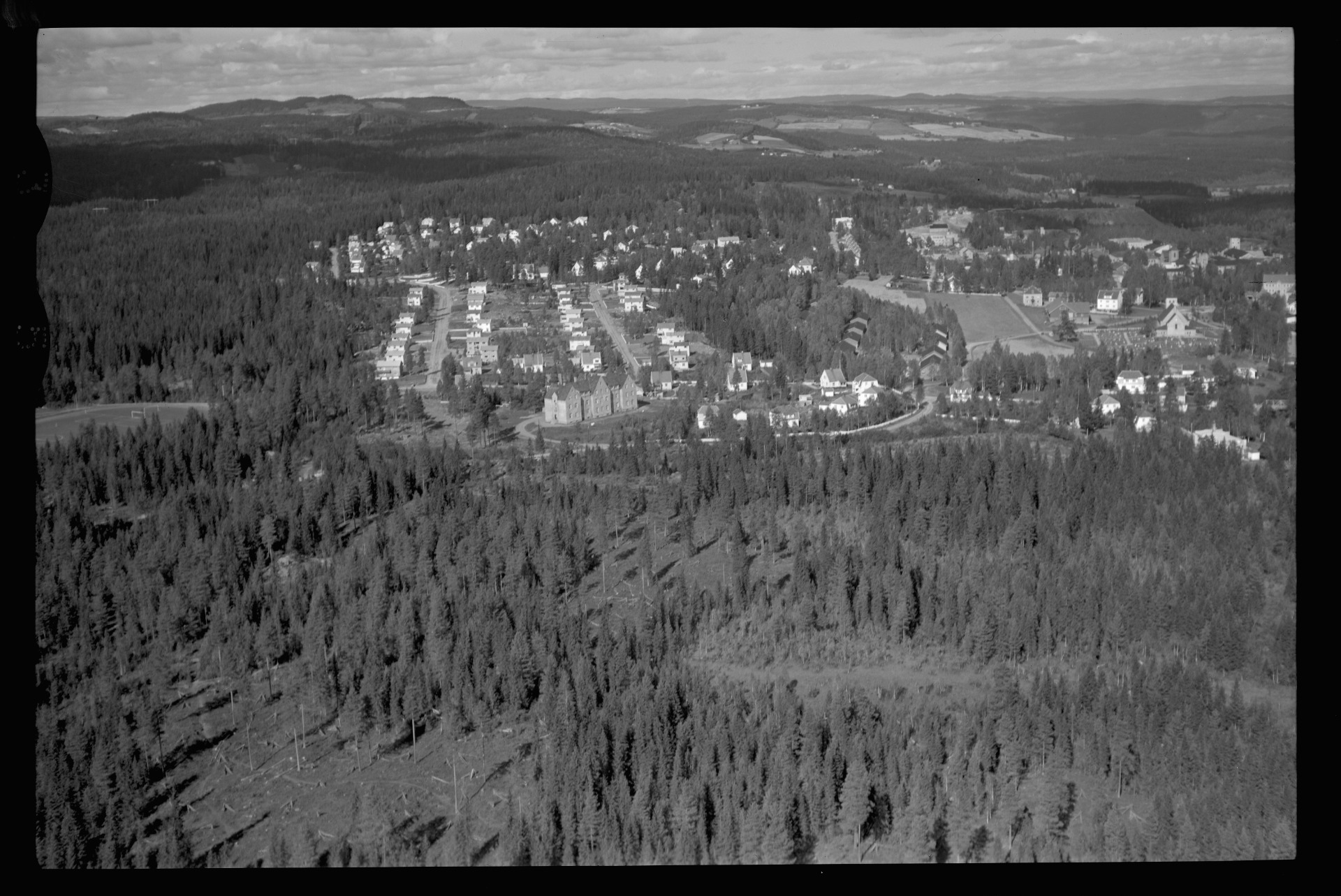 Raufoss sentrum sett fra syd med kassernen i front og vi kan se Arsenalbygningene mellom kirka og Kassernen. Flyfoto Widerøe 1954